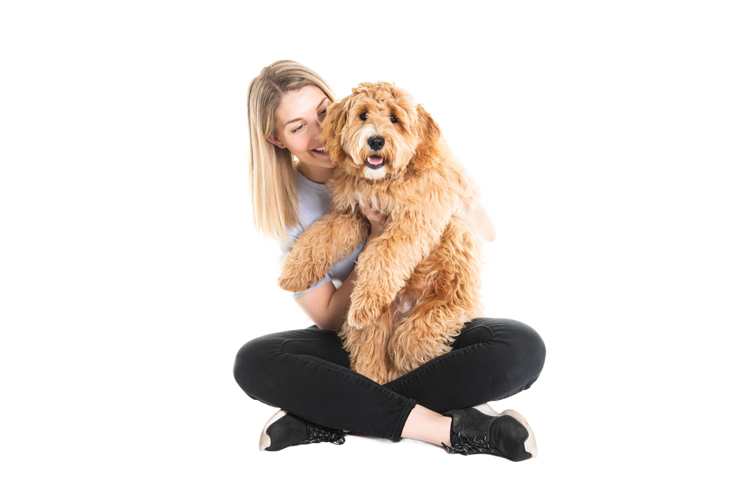 woman sitting cross legged holding a labradoodle