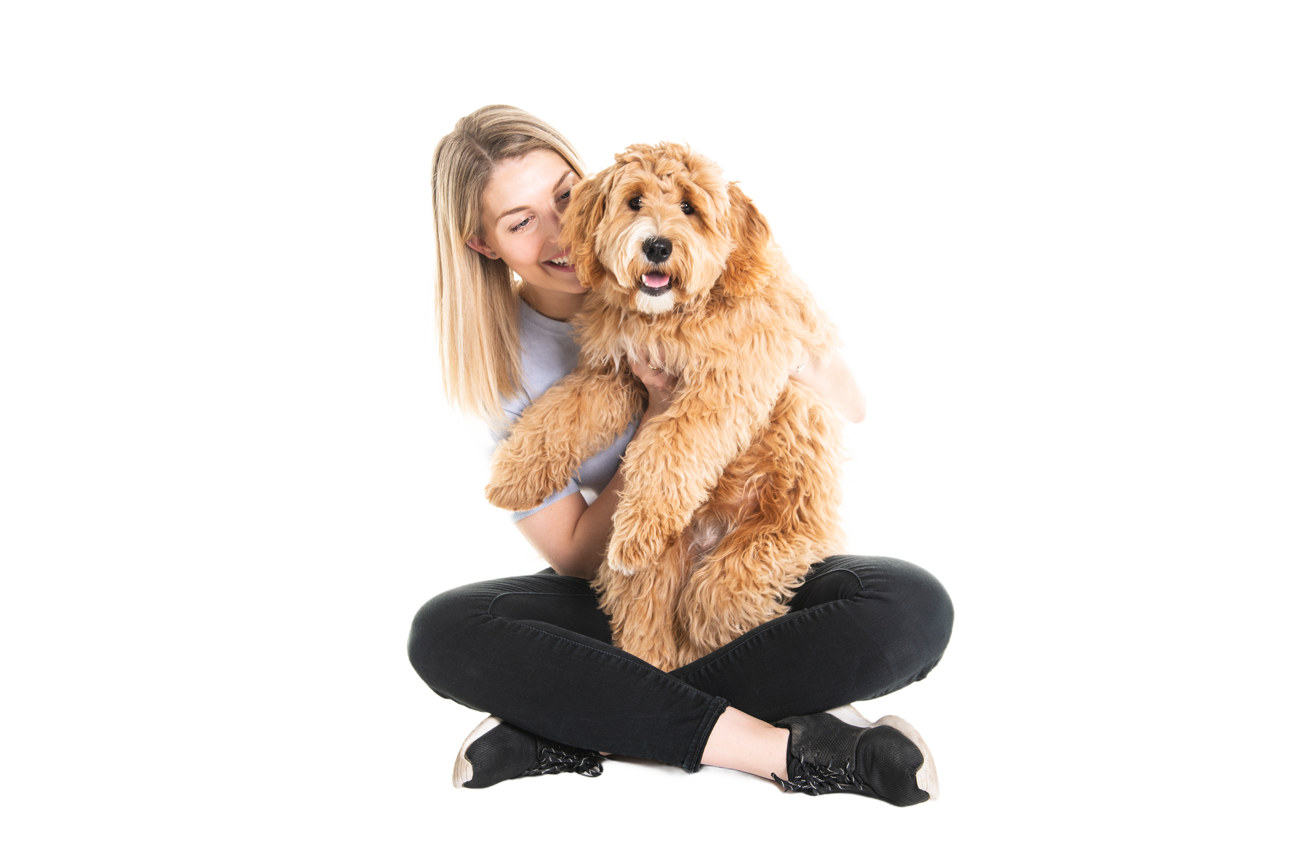 woman sitting cross legged holding a labradoodle